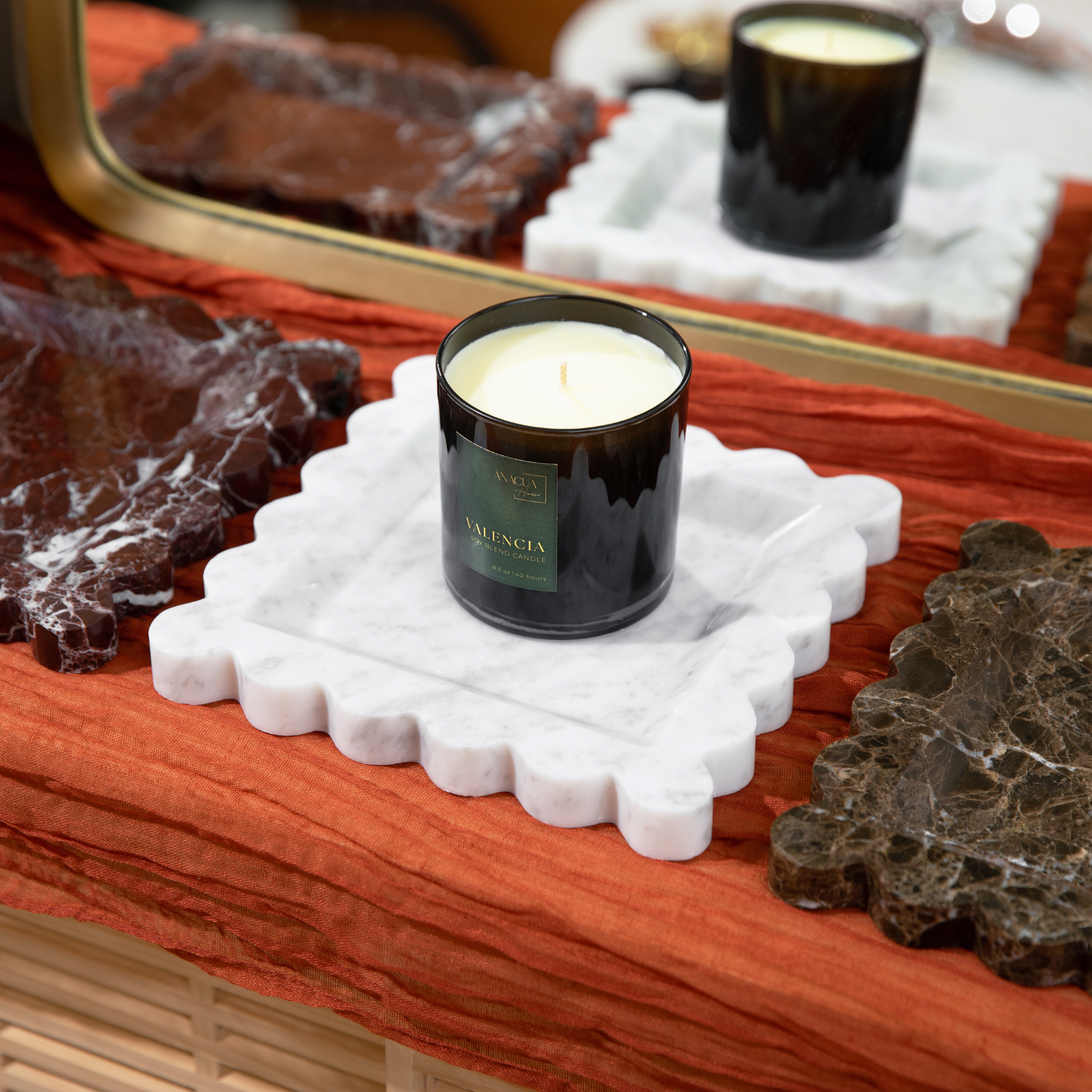 three candle trays with a black candle on a white marble dish
