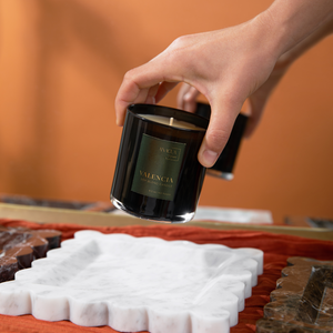 woman putting black jar candle on white marble candle tray
