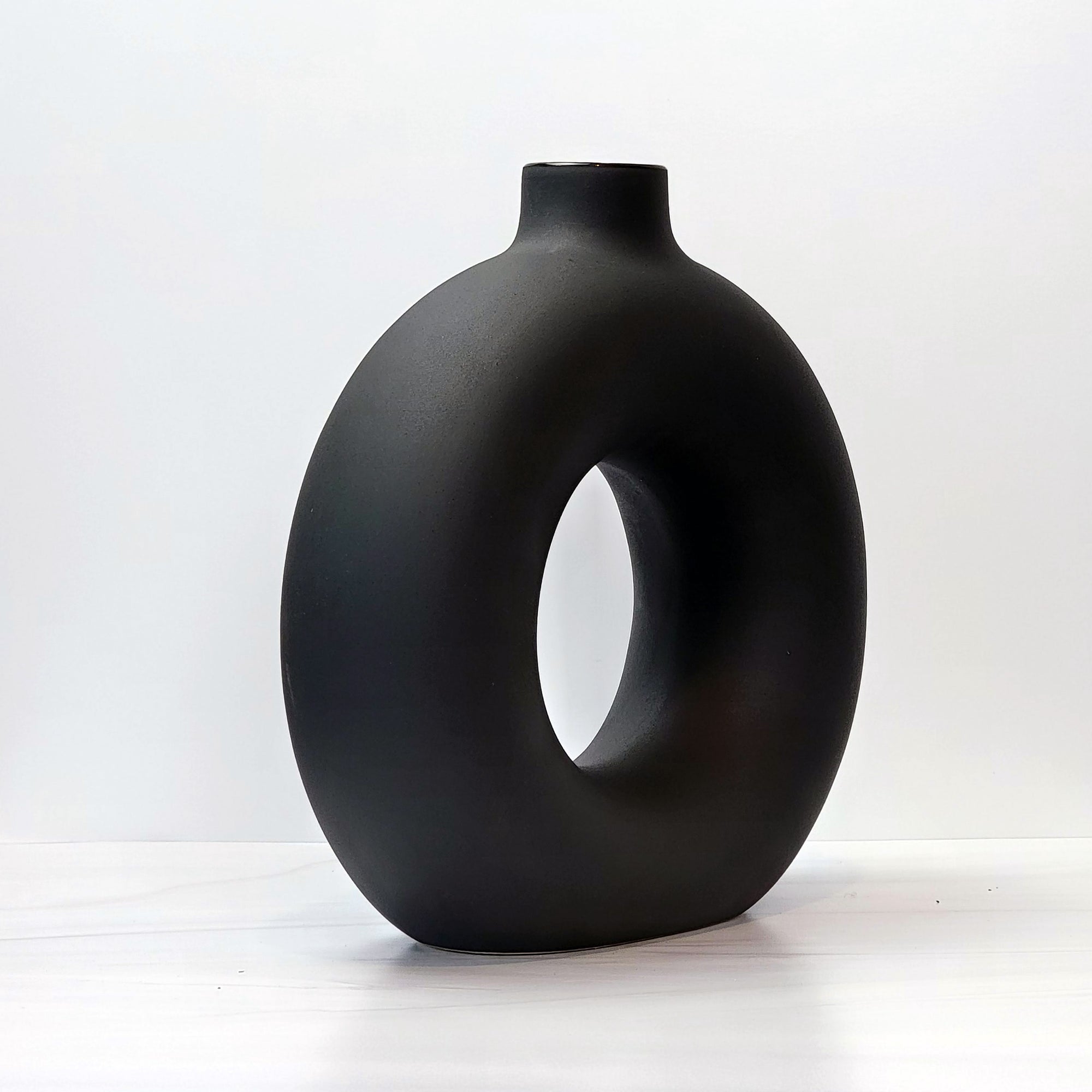 Large black doughnut-shaped Otto vase, angled.