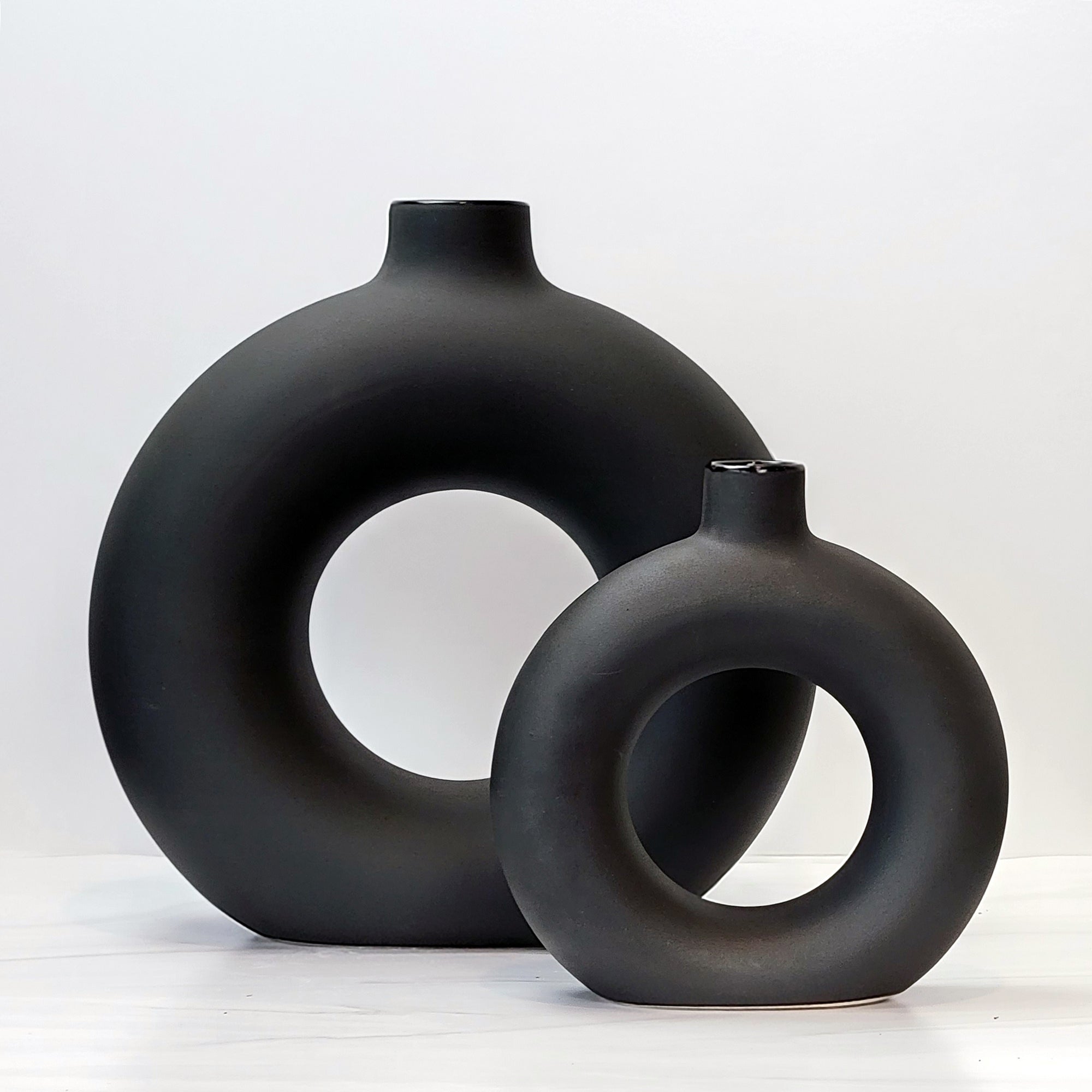 Large and small black doughnut-shaped Otto vases.
